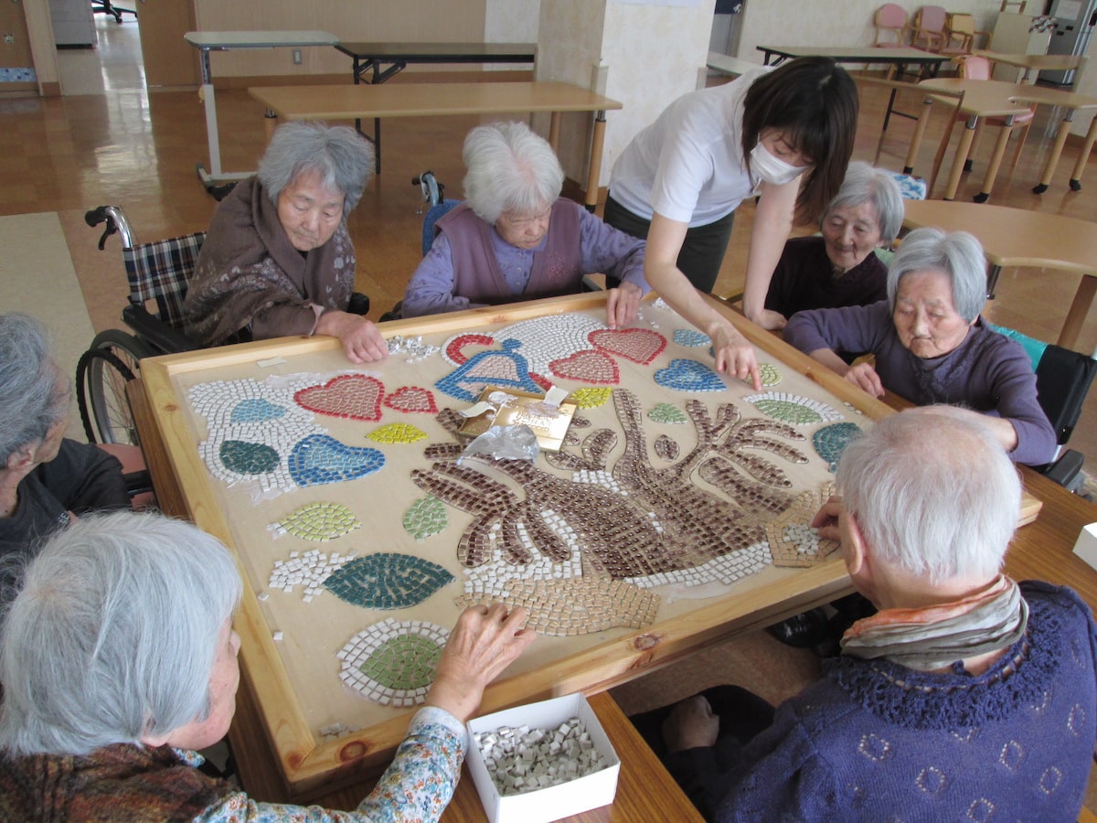 入居者と職員がモザイクアート制作活動に参加している様子。